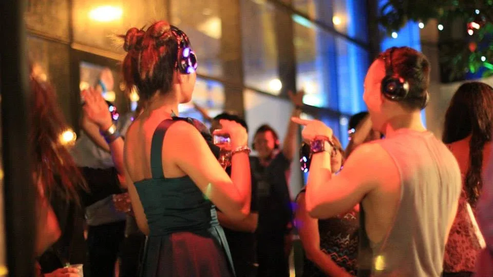 Guests dancing in headphones at the ACME party