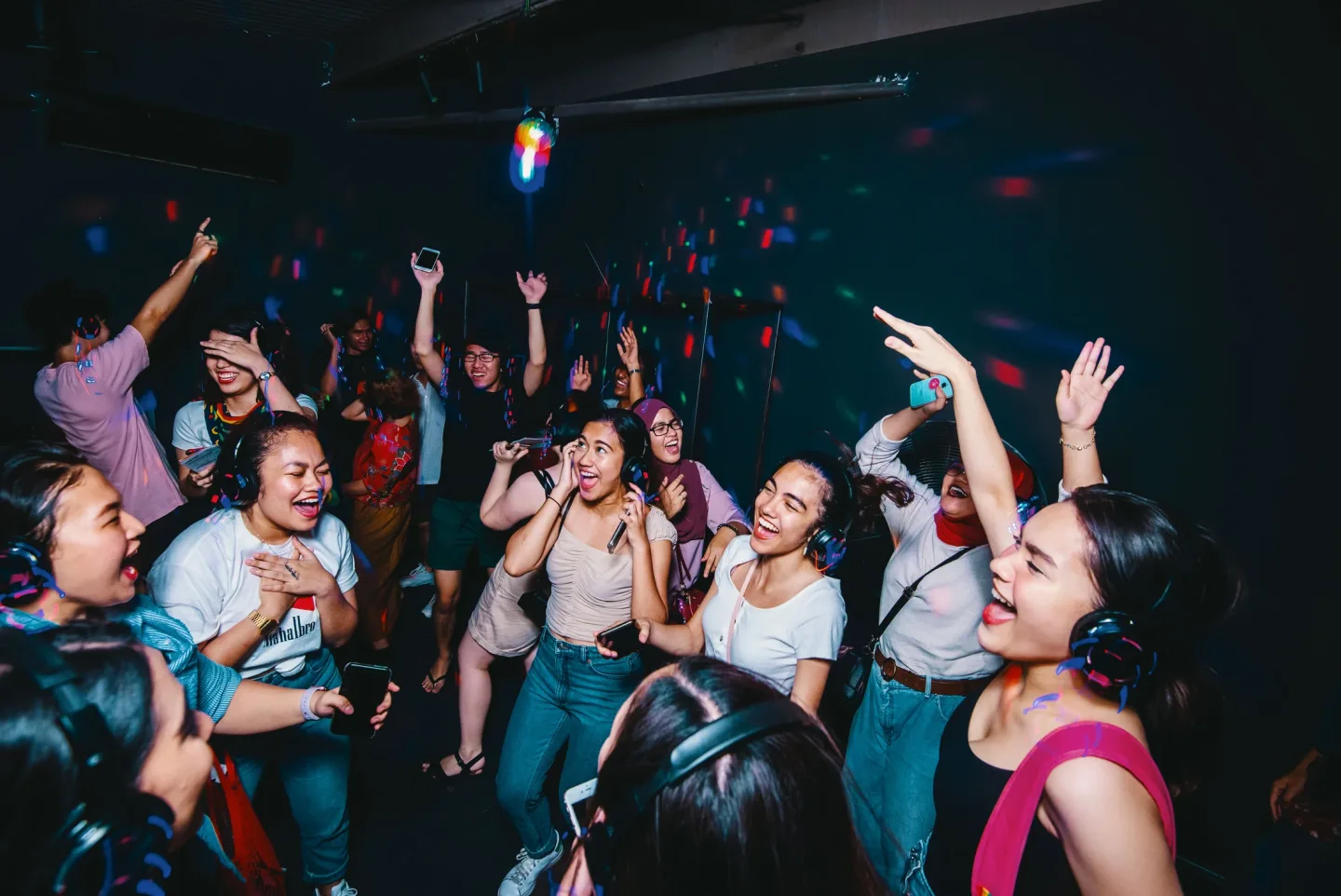 A RIUH dance floor with hands raised and illuminated headphones